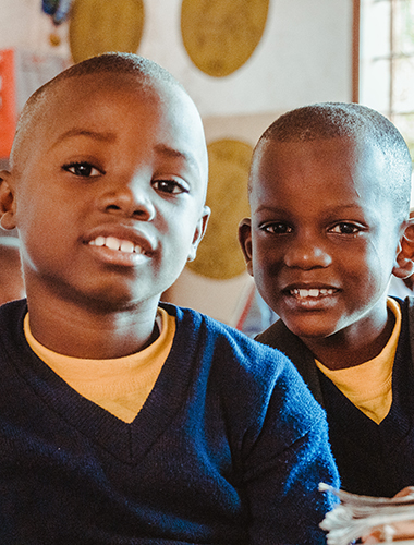 closeup shot two african children sitting classrom wearing sweater1